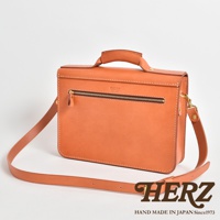 駝色皮革製成的手提公事包，帶有頂部提把、前方拉鍊口袋、可拆卸肩帶及品牌標誌。