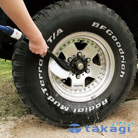 一個人正在用刷子清潔汽車輪胎，輪胎上有 BFGoodrich Radial T/A Mud-Terrain 的字樣。