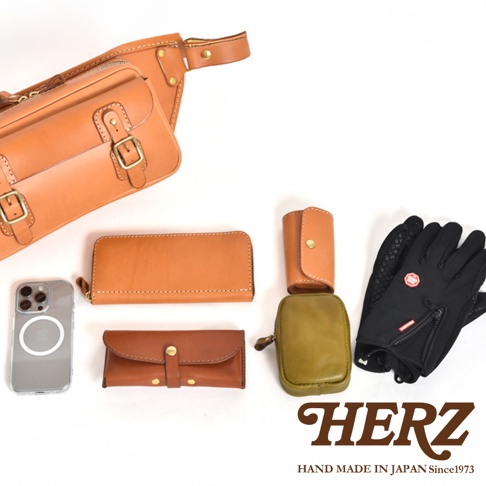 職人手作皮革騎士隨身斜背包 (F-12) 出現在圖片上方，顏色為原色皮革。旁邊擺放著咖啡色皮革長夾、咖啡色皮革鑰匙包、橄欖綠皮革小包、咖啡色皮革短夾、iPhone 手機及一雙黑色防滑手套。