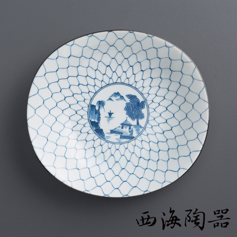 白色陶瓷淺盤，表面佈滿藍色網狀紋飾，中央圓形圖案描繪山水景致，包含山巒、樹木、小屋、小船與人物，盤緣為細黑邊。