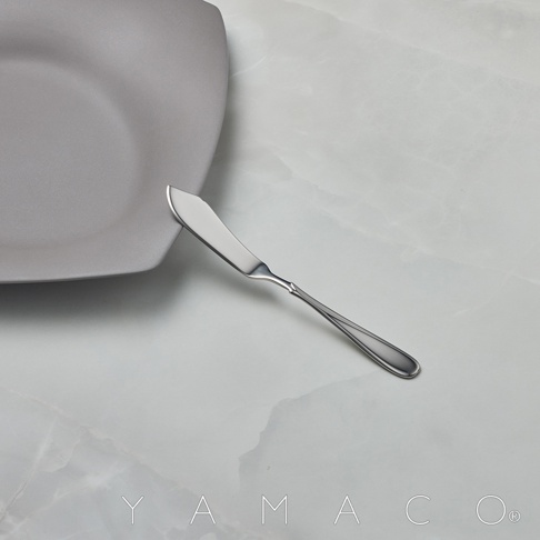 不鏽鋼奶油抹刀，帶有曲線造型的把手，放置於灰色盤子旁，背景為大理石紋桌面。