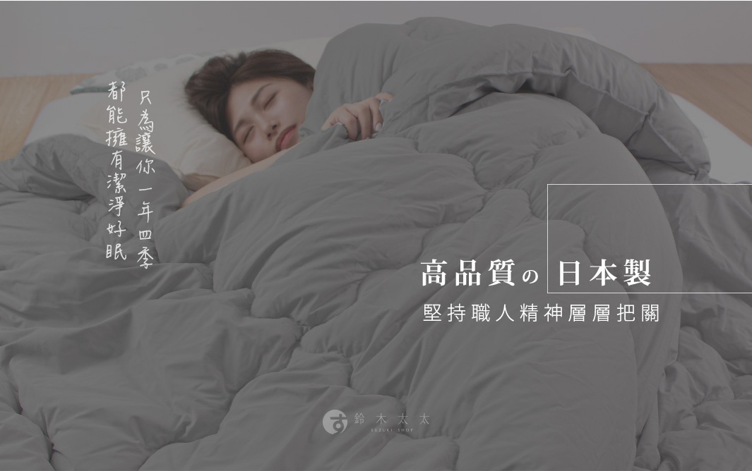 一條覆蓋著熟睡女性的灰色被子，上面印有日文和中文標語，包括「高品質」和「日本製」。
