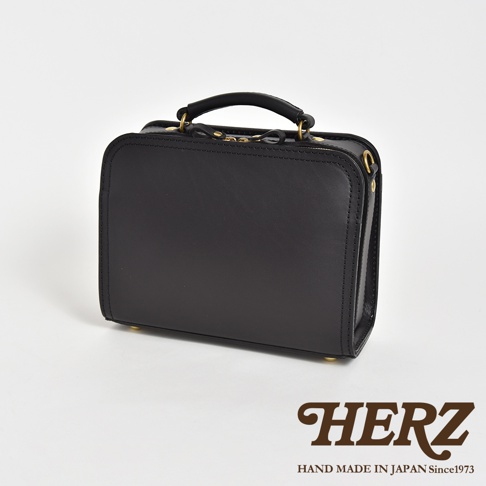 職人手作皮革兩用方形單肩包，黑色皮革，方形包身，頂部有提把，附有可拆卸肩帶，金色金屬拉鍊和扣環。