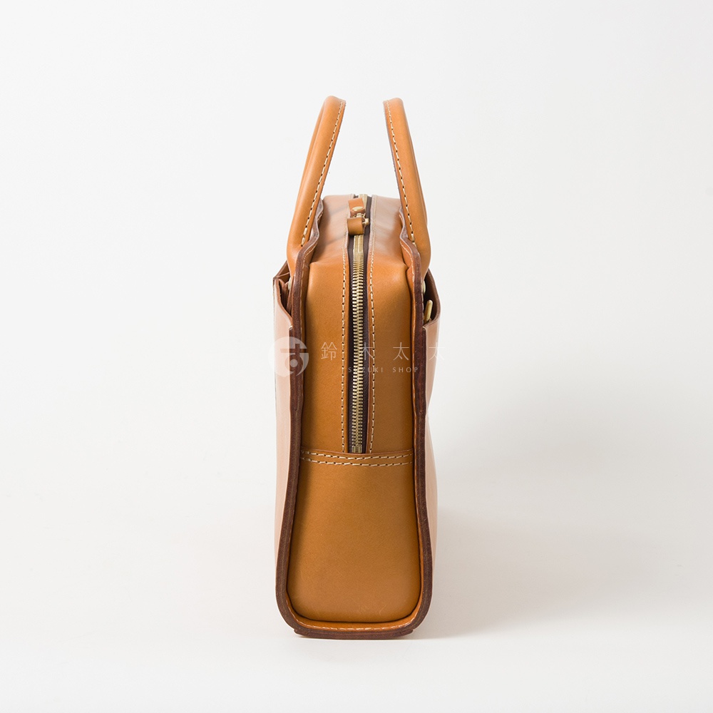職人手作皮革雙口袋兩用商務公事包，採用棕褐色皮革製作，包款側邊可見拉鍊開合與縫線細節，配有圓形提把。