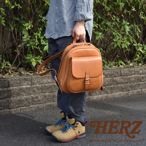 棕色皮革迷你後背包，有立體前袋和皮帶扣，雙肩帶，適合休閒搭配。