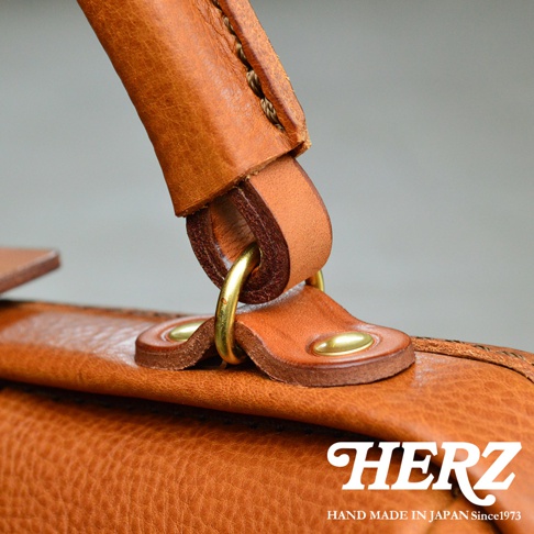 職人手作皮革Organ方形口金托特包，特寫展示包包提把與側面皮革細節，使用淺棕色皮革，搭配黃銅色金屬釦件，皮革表面紋理清晰，縫線工整。