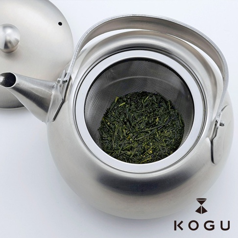 日製18-8不鏽鋼急須茶壺，壺身呈現銀色金屬光澤，附有細網濾網，壺內裝有乾燥的綠色茶葉。