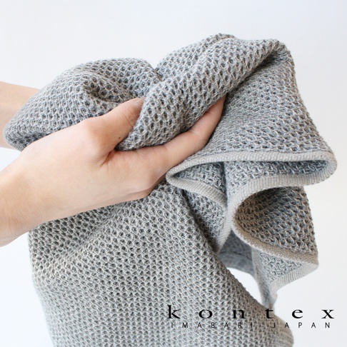 KONTEX IMABARI JAPAN VINTAGE鬆餅紋棉麻混紡毛巾，灰色，一隻手正在抓握。