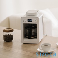 白色 SC-A3520 自動研磨咖啡機，搭配玻璃咖啡豆罐和白色咖啡杯，置於木質桌面。咖啡機正面有黑色操作面板、數位顯示螢幕及玻璃咖啡壺。