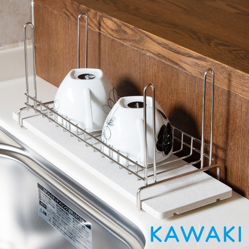 珪藻土材質的白色瀝水盤上，放置著一個金屬支架，支架上擺放著兩個白色陶瓷碗，碗身有黑色花紋圖案。