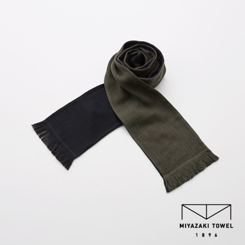 今治匹馬棉雙色圍巾，一端為黑色，另一端為墨綠色，兩端皆有流蘇，材質柔軟。
