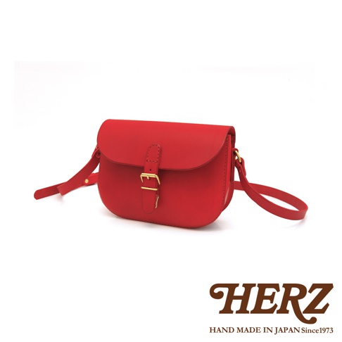 紅色皮革經典馬鞍包，配有金屬釦和可調式肩帶，包身線條簡潔，展現職人手作質感。