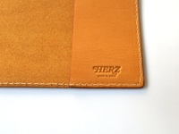 職人手作皮革A4筆記本書套，淺棕色皮革內襯，外層為質感光滑的橘棕色皮革，壓印有「HERZ MADE IN JAPAN」字樣，邊緣以白色車線縫合。