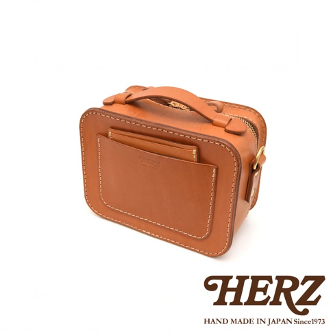 日本HERZ職人手作皮革兩用迷你小方包CW-40，棕色硬皮革材質，箱型設計，正面有插袋，上方有提把，側面有金屬扣環，印有HERZ字樣與HAND MADE IN JAPAN Since1973。