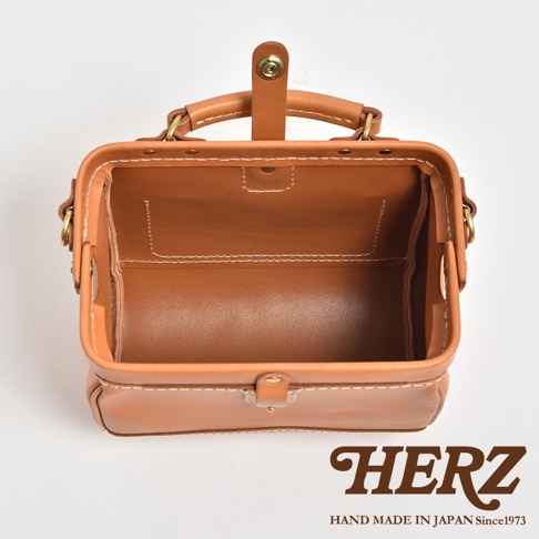 職人手作皮革口金醫生單肩包，採用棕色皮革製成，配有金色金屬配件及白色縫線，包身結構方正，頂部設有提把及開闔扣。