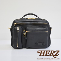 黑色皮革手提斜肩兩用包，包身有多個拉鍊口袋，金色拉鍊與金屬配件，頂部有提把，側面有肩帶掛環，品牌標誌壓印於前袋下方。