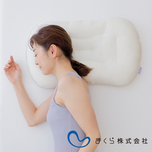 一位女性側臥，頭部倚靠在白色網格紋理、帶有凹槽設計的調節枕上。