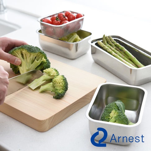 Arnest 不鏽鋼多功能濾網保鮮盒 3 件組，展示了正在切BROCCOLI的場景，其他保鮮盒中裝有番茄和蘆筍，呈現整潔的廚房備料氛圍。