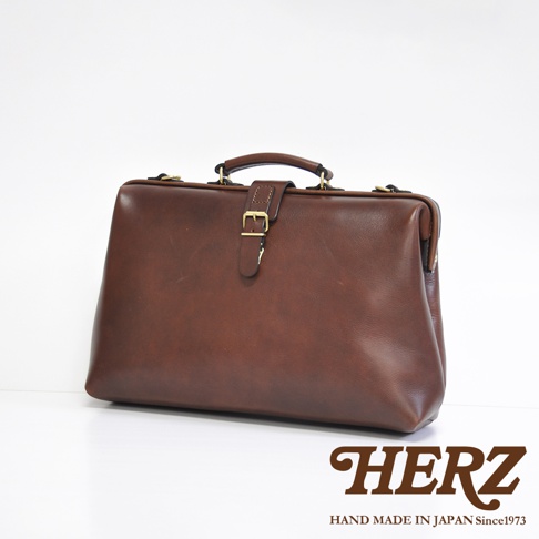 職人手作皮革軟式杜勒斯包，深棕色，復古醫生包造型，頂部有提把，正面有金屬扣帶設計，材質為光滑皮革。