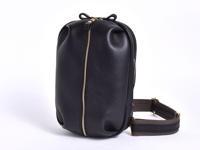 職人手作黑色皮革立體運動斜背包，設有金色拉鍊和織帶背帶，風格簡約實用。