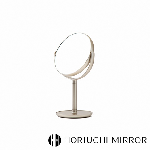 香檳金色金屬材質的桌上型化妝圓鏡，鏡面可調整角度，底座為圓形。