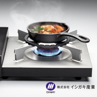 五德瓦斯爐架，銀色金屬爐身，黑色爐架，爐頭火焰為藍色，上面放著一個黑色鑄鐵小鍋，鍋內有烹煮中的蝦和香草，鍋身有白色蒸氣冒出。