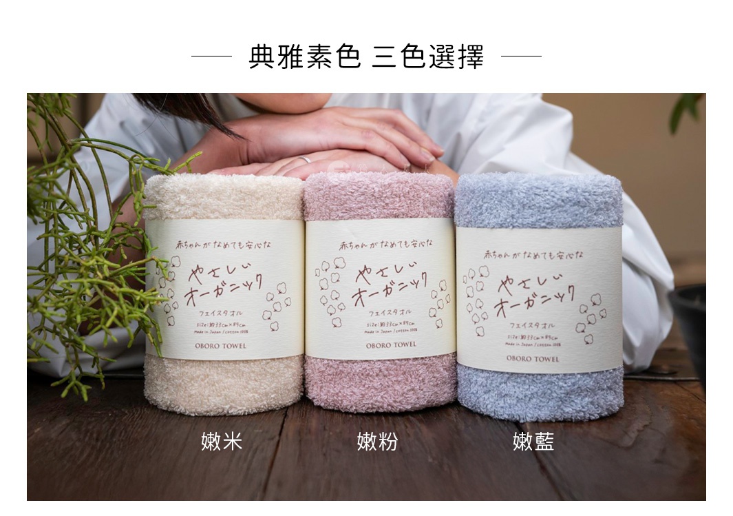 三條捲起的有機棉浴巾，分別為米色、粉色和藍色，皆有日文標籤。