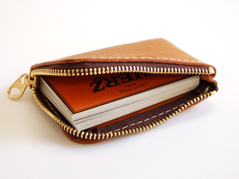 職人手作的淺棕色荔枝紋軟皮革L型拉鍊卡片夾，內含一疊厚約2公分的卡片，拉鍊為金色，縫線為淺褐色。