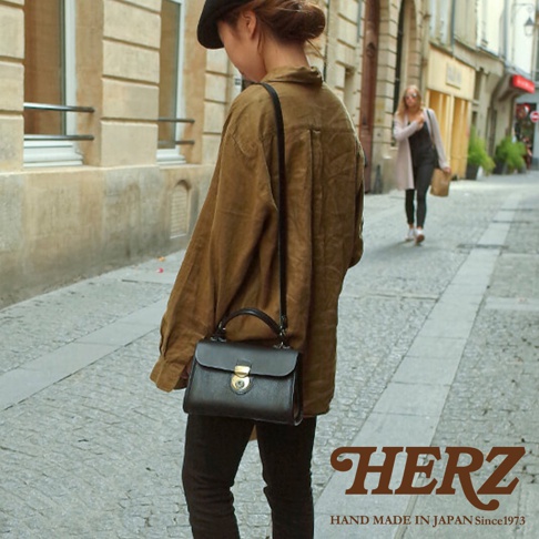 職人手作皮革迷你手提包，黑色，配有金色鎖扣及可拆卸斜背帶。包款設計簡潔，質感皮革，展現俐落風格。