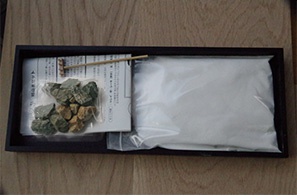 日本枯山水模型，京都龍安寺監修款。包含白色細沙一包、綠色和褐色石塊數顆，以及一把迷你耙子，所有物品擺放在深棕色木製托盤內。