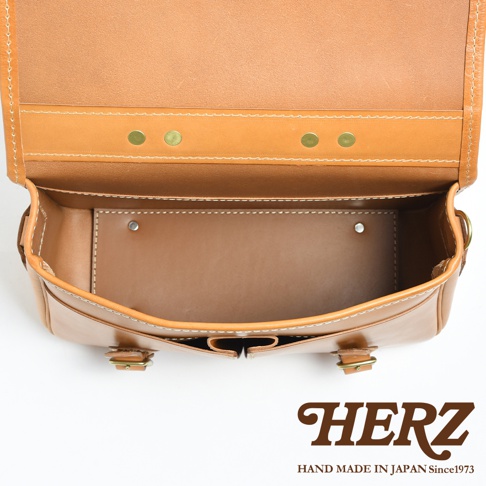 職人手作皮革商務休閒兩用單肩包，展現天然皮革的溫潤質感，包身採經典棕褐色，搭配白色縫線與古銅色金屬釦，簡約而堅固的結構，適合各式場合。