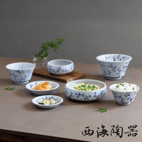 六件式白色陶瓷碗盤組，飾有藍色植物花紋，包含不同尺寸的碗，其中一些盛有食物，如麵條、米飯、炸蝦和櫛瓜片。