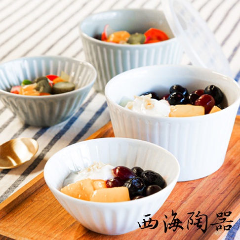 波佐見燒 FUWARI 四件式碗碟，白色與淺藍色陶瓷材質，碗身帶有垂直壓紋設計。其中兩個碗內盛有水果優格，另一個碗內盛有漬物，背景是條紋布料和木盤。