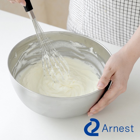 Arnest 不鏽鋼調理碗中，手持打蛋器正在攪打奶油，碗旁有 Arnest 品牌標誌。