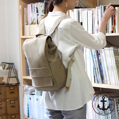 卡其色高島帆布前蓋式背包，配有側袋和可調節肩帶，適合日常使用。