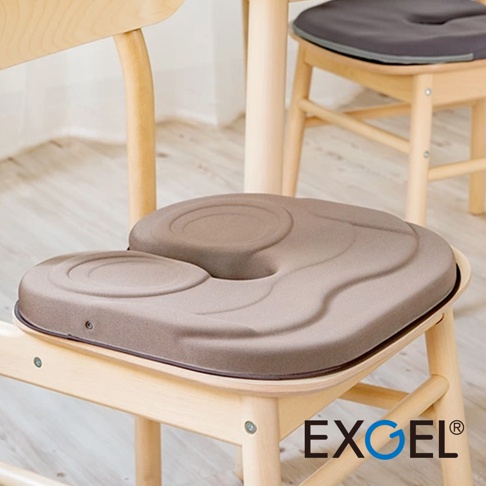 THE OWL Standard U貓頭鷹U字型基本款坐墊，採用淺棕色布料，坐墊表面有U型凹槽和同心圓紋路設計，材質柔軟厚實，放置於木製椅子上。