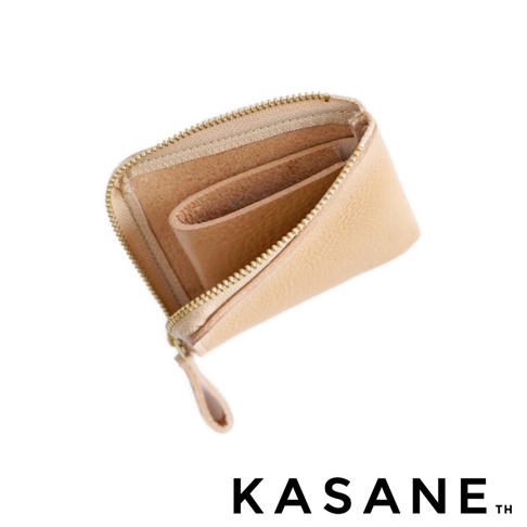 一個北海道KASANE品牌職人手作的淺米色義大利Vachetta Box皮革L型拉鍊短夾，以俯視角度呈現，展示出簡約的皮革紋理與拉鍊細節，下方標註KASANE品牌名稱。