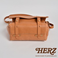 職人手作皮革復古郵差包CM-100，淺棕色，全粒面皮革材質，設有雙皮帶扣蓋和金屬釘裝飾，風格簡約實用。