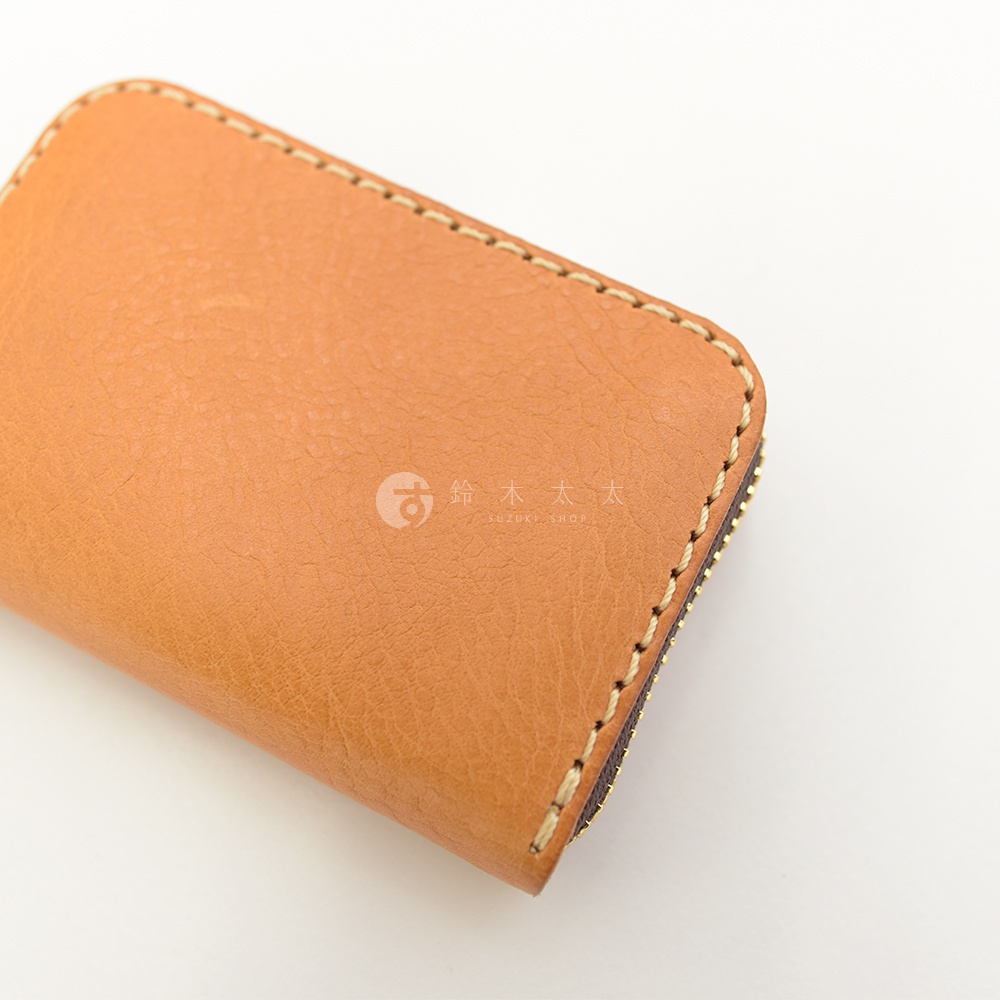 淺棕色皮革製成的拉鍊錢包，帶有手工縫線細節。