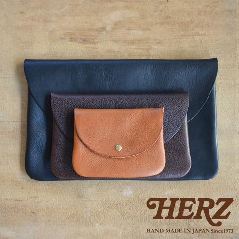 三款職人手作皮革小物收納袋，由左至右分別為黑色、深棕色、淺棕色，皆為鈕扣式設計，材質為皮革。