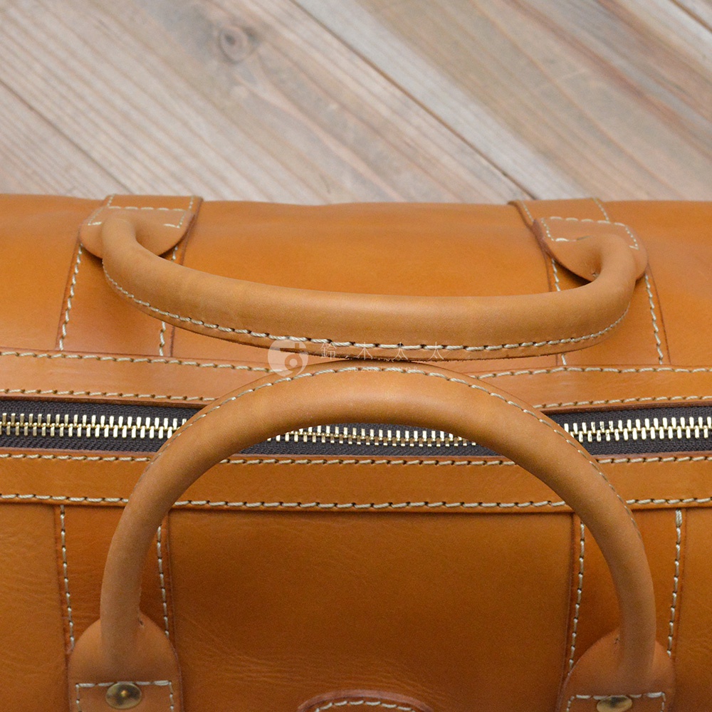 職人手作皮革肩背手提拉鍊波士頓包，採用棕褐色皮革，縫線精緻，設有雙提把及拉鍊開口，展現經典波士頓包款。