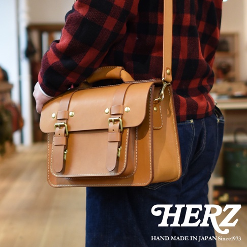 職人手作皮革經典雙扣兩用單肩包，棕褐色皮革，配有黃銅色金屬扣環和細緻縫線，可作為單肩包或手提包使用。