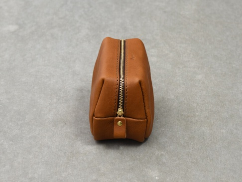 一個棕褐色的皮革收納包，頂部有金色拉鍊，底部有皮革拉環和金色扣件。