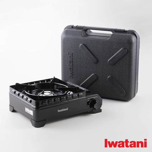 黑色金屬卡式爐，爐面有黑色支架，旁邊有一個黑色塑膠收納盒，盒上有「Iwatani」字樣。