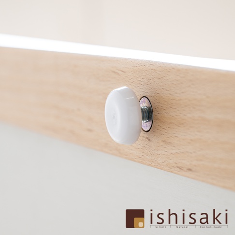 木製畫板上的白色圓形旋鈕，固定於淺木色木條上，旋鈕旁有金屬螺絲及墊圈。