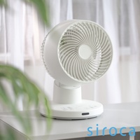 SF-A1610 3D氣流循環扇，白色塑膠材質，扇葉呈漩渦狀，可調角度，底座有觸控按鈕與指示燈，背景為白色窗簾與綠色植物。