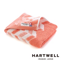 一條珊瑚橙色與白色相間的毛巾，以傳統和風紋樣織成，質感柔軟，帶有 HARTWELL IMABARI JAPAN 的標籤。