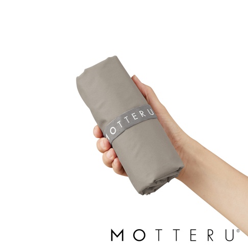 一手持著一個捲起的灰色摺疊保冷袋，袋子上有一條灰色的束帶，上面有白色「MOTTERU」字樣。