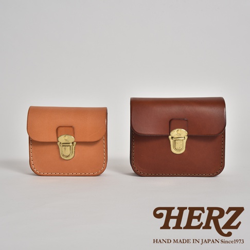 兩個職人手作皮革腰包，一個為淺棕色，另一個為深棕色，皆採用經典翻蓋設計，配有金色金屬鎖扣，展示皮革的自然紋理與精緻縫線。