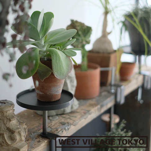 黑色圓形鐵製可夾式小物桌，附有銀色金屬支架，可夾於木質檯面上，上方擺放著盆栽植物。